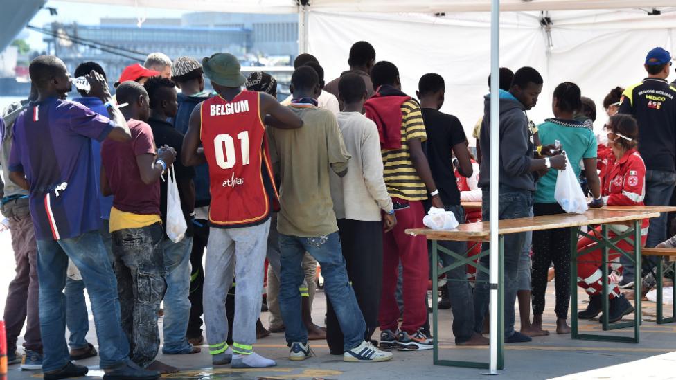 Migrants line up at a Red Cross tent after they disembarked from a rescue vessel at the Messina harbour in Sicily, Italy - 24 August 2015