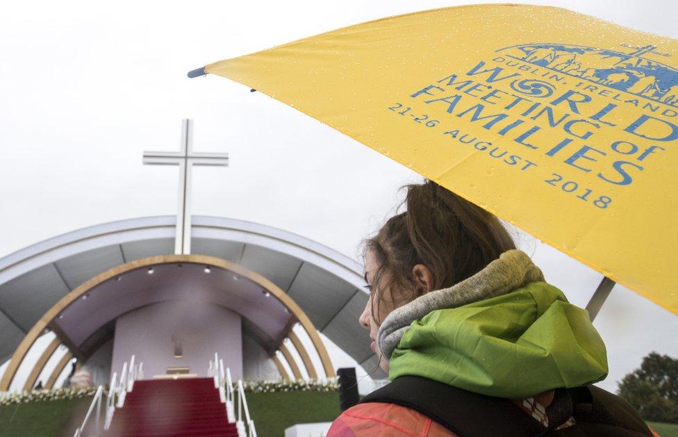 A woman stands under an umbrella ahead of the papal mass at the World Meeting of Families in Phoenix Park in Dublin