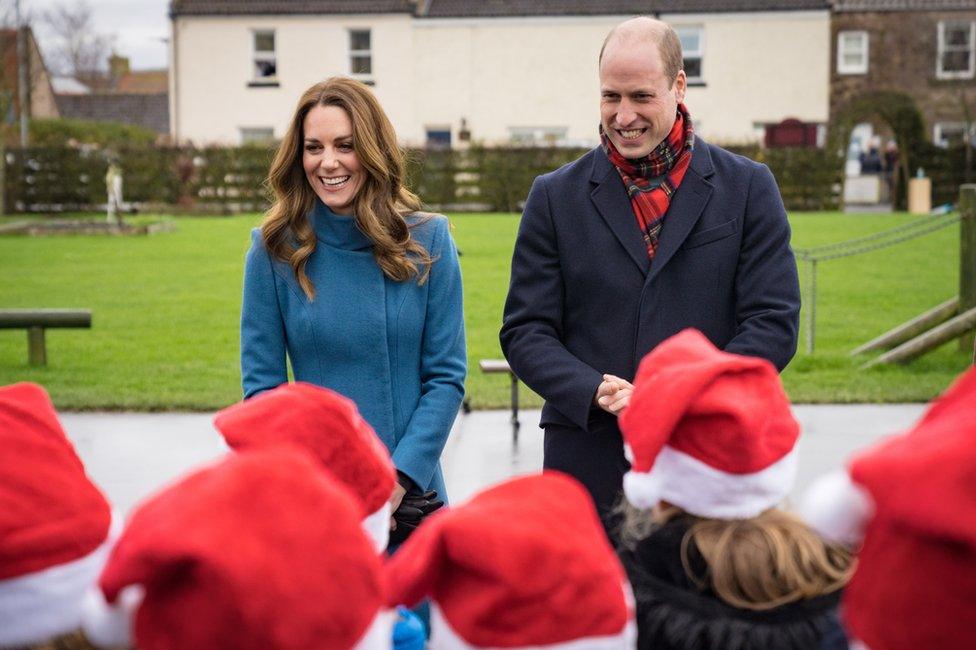 Schoolchildren wearing santa hats meet Kate and William