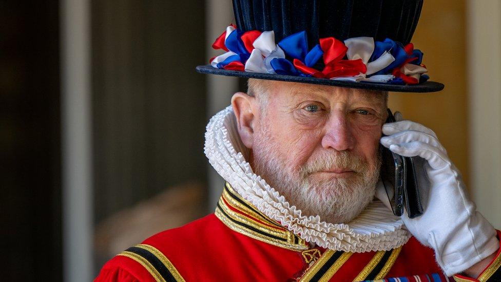 A Yeoman of the Guard speaks on a mobile phone