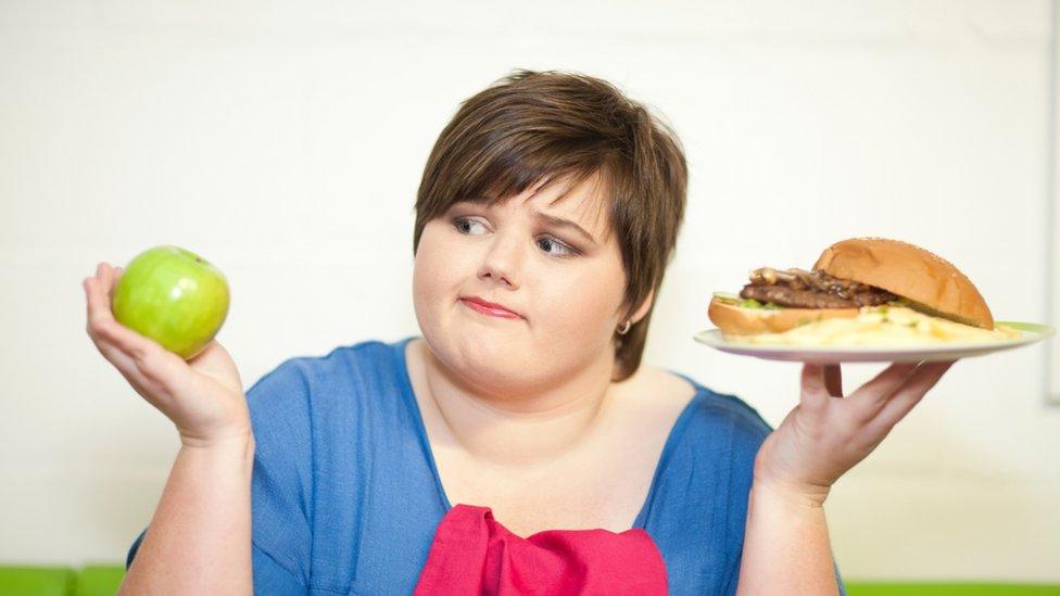 Woman choosing between apple and burger