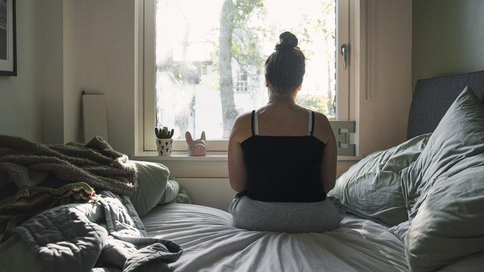 Stock image of a woman looking aout of a window