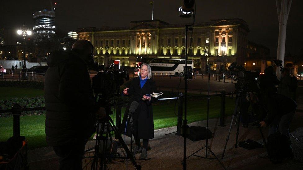 journalists reporting the news about the king outside buckingham palace at night