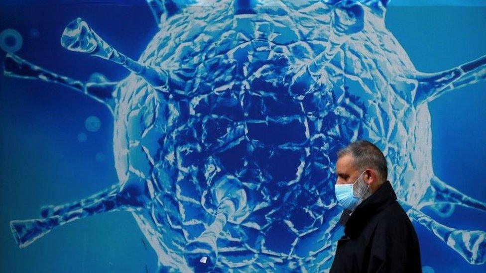 A man walking past a coronavirus poster