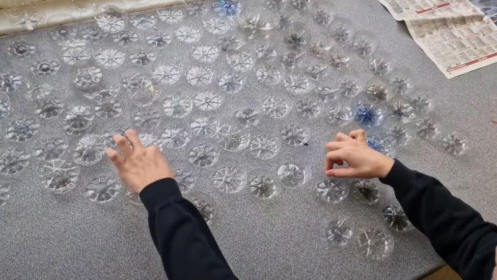 A student cutting bottles into poppies