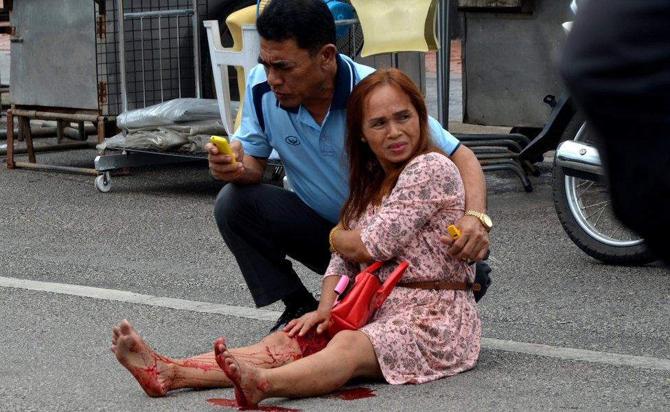 An injured woman sitting in the road after a bomb exploded on 11 August 2016 in Trang.