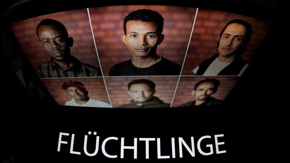 Computer screen in Hannover displaying pictures of refugees with the word "Fluechtinge" (Refugees)