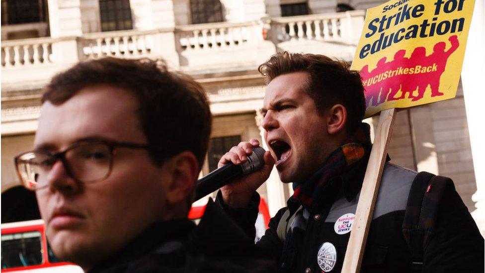 A member of University and College Union (UCU) chants slogans while holding a placard during the demonstration