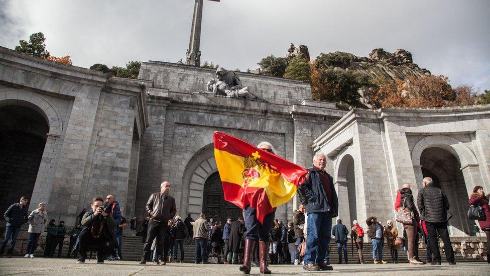 A woman waves a Spanish flag outside the Valley of the Fallen memorial near Madrid