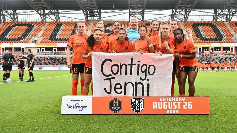 The row has spread beyond Spain, with Houston Dash players holding a sign reading "with you Jenni" ahead of their match against Kansas City Current