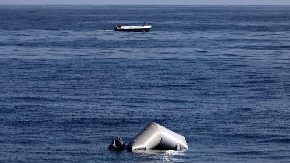 A Libyan fisherman speeds past the remains of a migrant raft in central Mediterranean Sea off the Libyan coast during a search and rescue operation by Spanish NGO Proactiva Open Arms