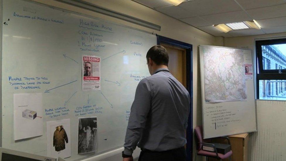 A police officers assessing a missing persons board at Halifax police station