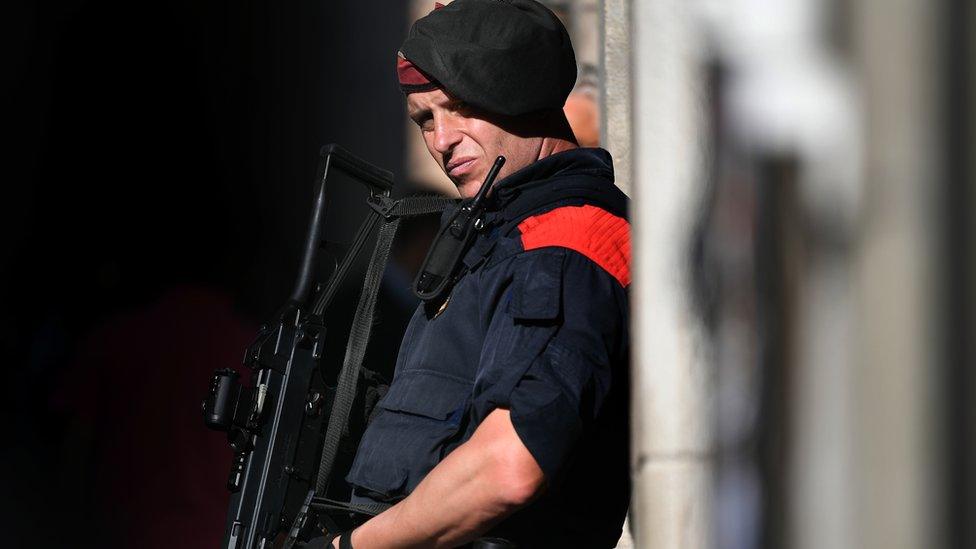 Policeman leaning against wall, carrying gun