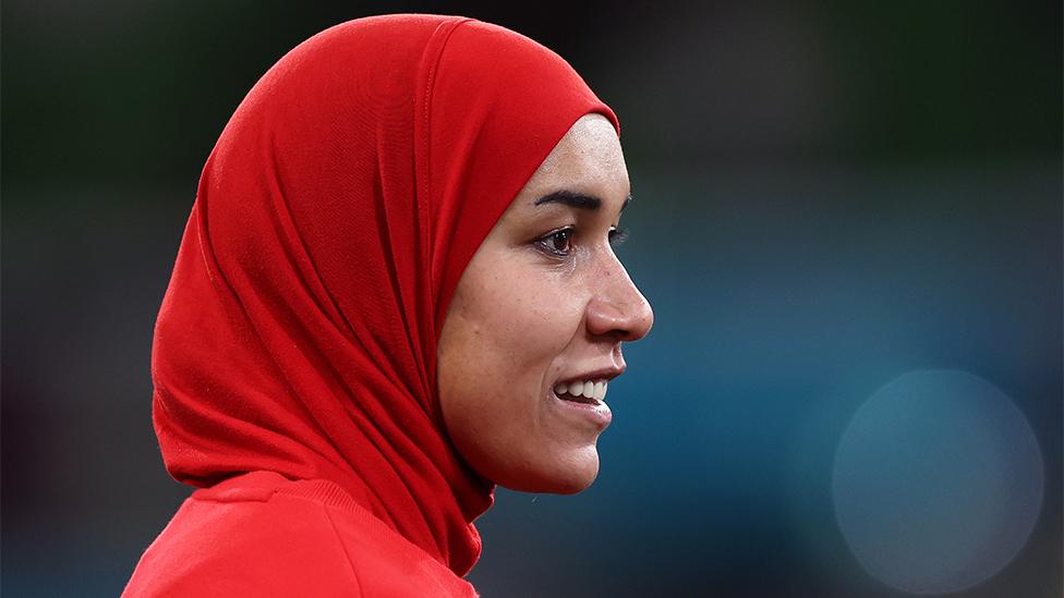 A side profile of Nouhaila Benzina from Morocco. She's wearing a red hijab, looking into the distance.