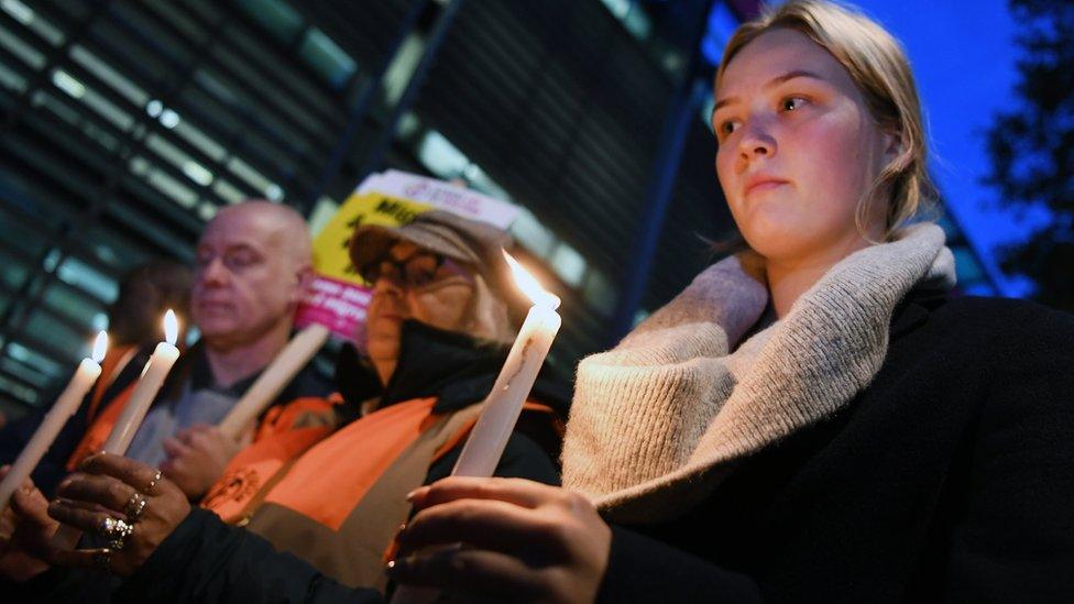 People hold candles at a vigil