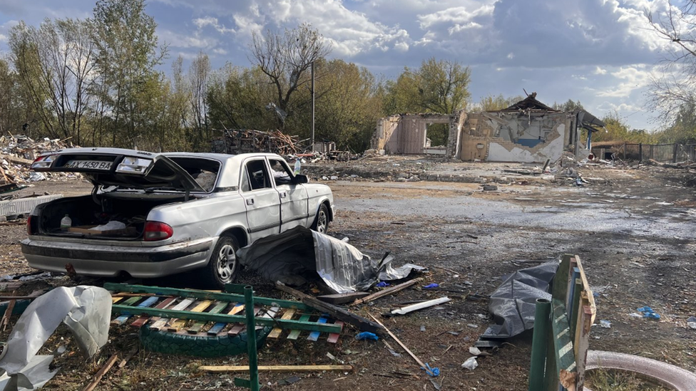 Debris of a car and buildings in Hroza after a missile strike killed 52 people