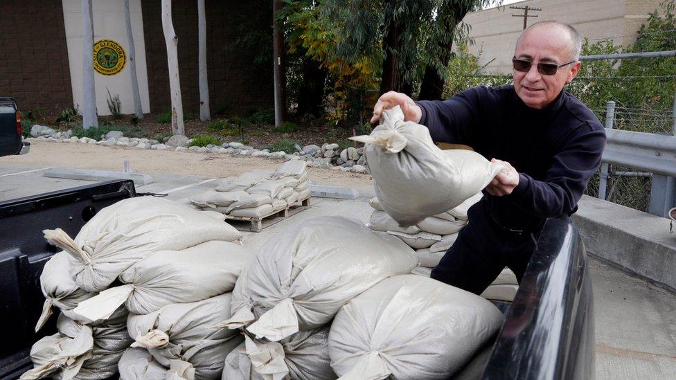 A man piles sandbags into his truck