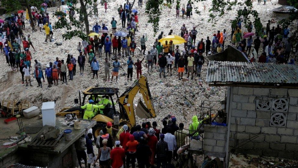 Residents look at workers at an area affected by the passage of Tropical Storm Laura, in Port-au-Prince, Haiti