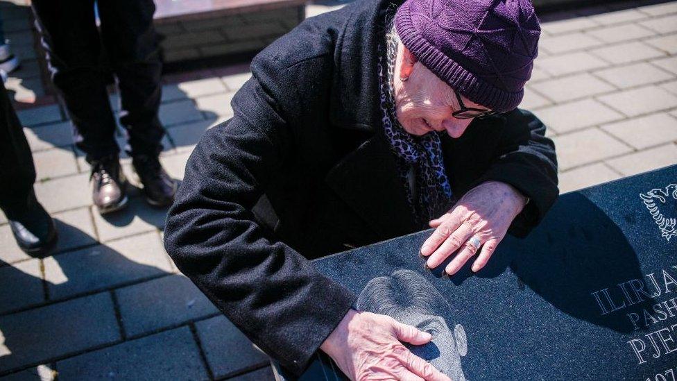 A woman cries over the grave of her brother in Kosovo on the Day of Missing Persons