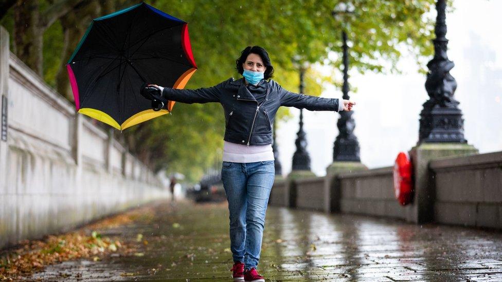 A woman is seen walking through the rain at Westminster