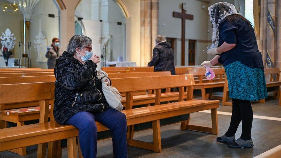 A woman cleans as members of the public pray at St Andrew Cathedral as places of worship reopen for private prayers