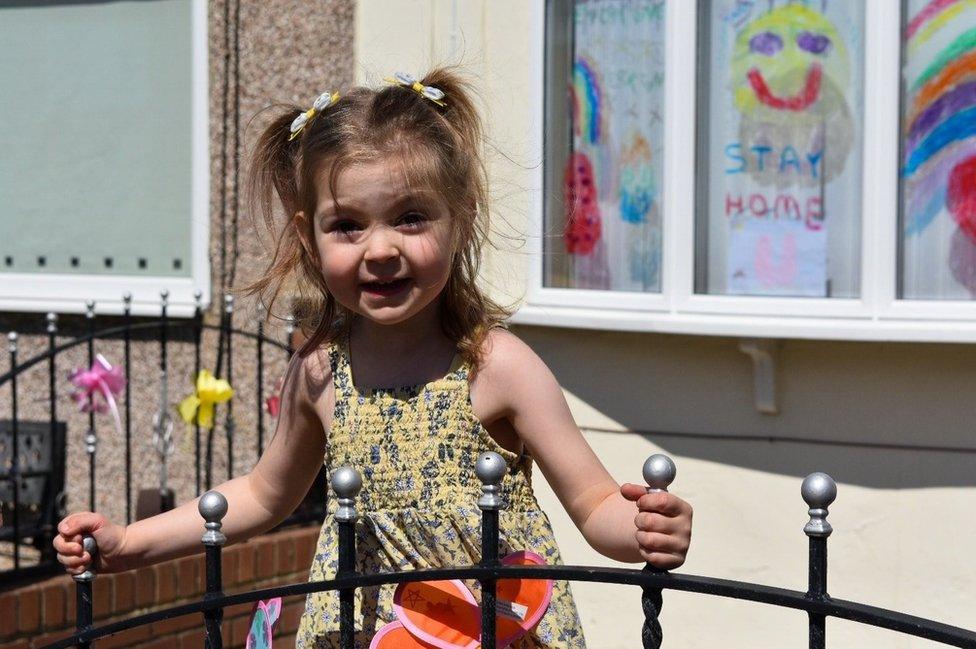 A smiling young girl in her front garden