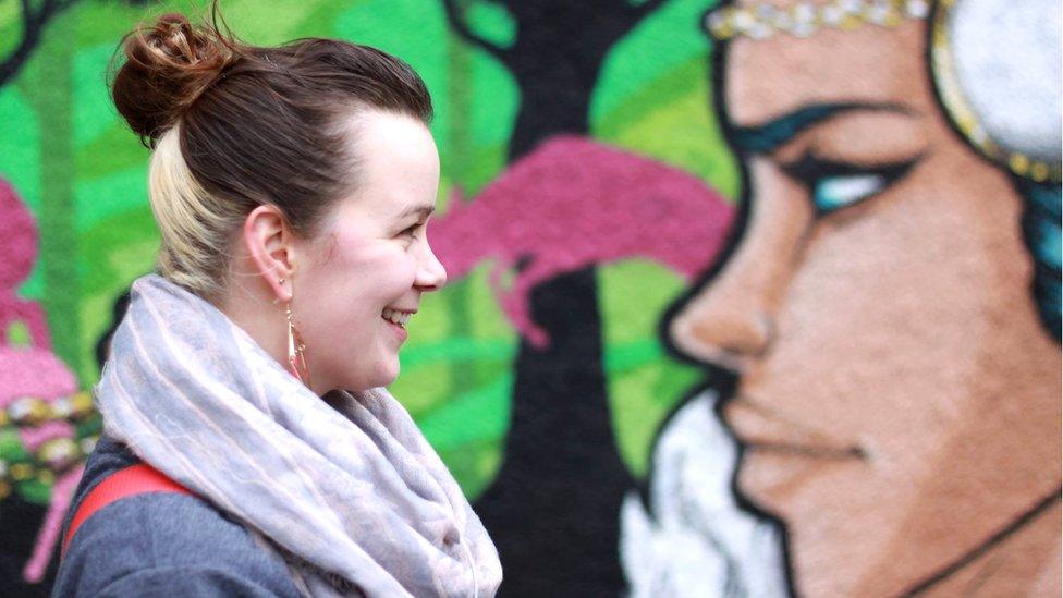 Side profile of artist looking at side profile of one of her paintings