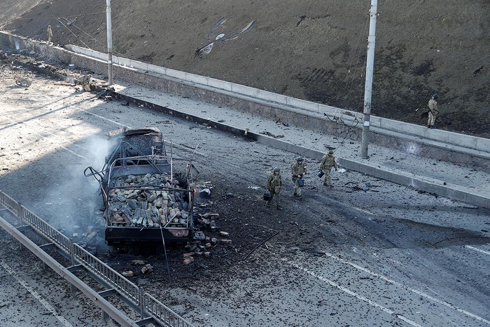 Ukrainian servicemen walk by a damaged vehicle, at the site of fighting with Russian troops, , in Kyiv, Ukraine February 26, 2022.