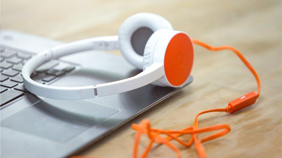 A pair of headphones sitting next to a laptop computer