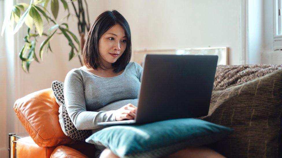 A woman works on her laptop on the sofa