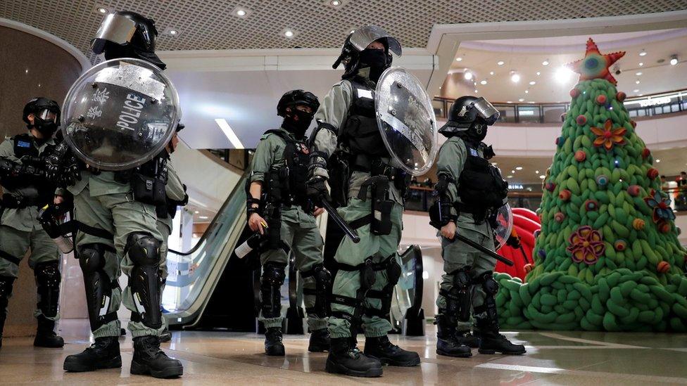 Riot police stand guard next to a Christmas tree inside a shopping mall during an anti-government protest on Christmas Eve at Tsim Sha Tsui in Hong Kong, China, December 24, 2019