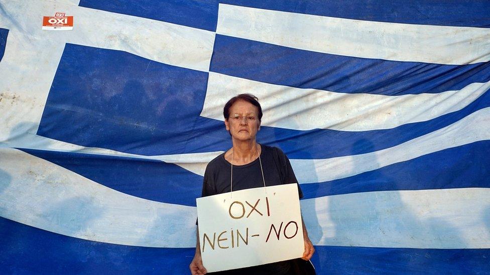 Woman protesting in front of the Greek flag