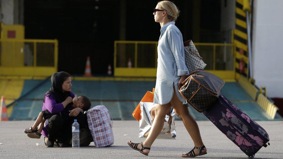 A traveller passes an Afghan woman breastfeeding her baby at the Athens port of Piraeus, 7 September 2015