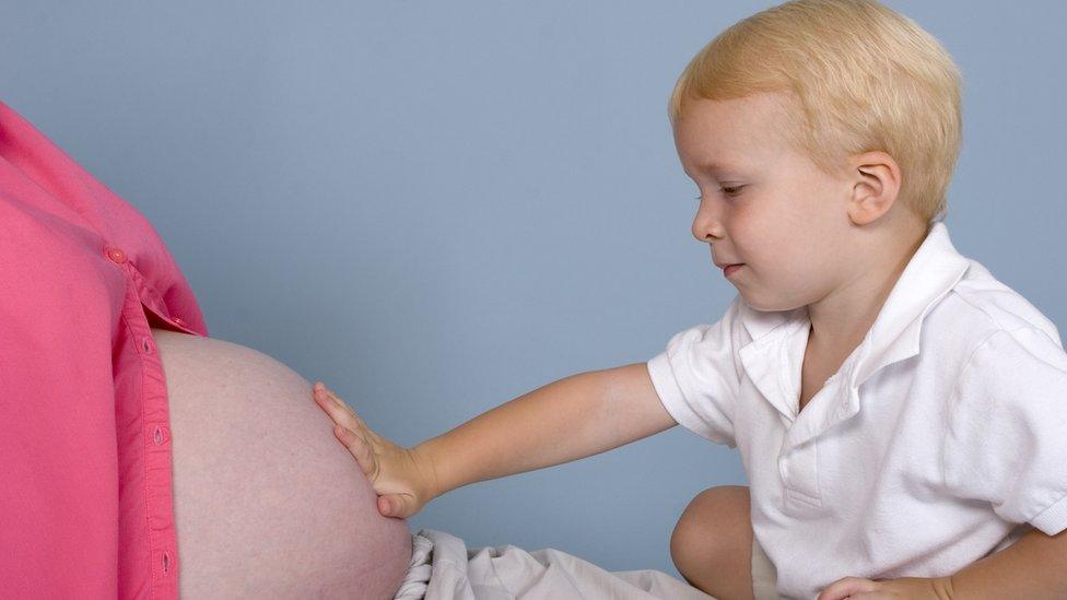 young boy touching his mum's pregnant belly