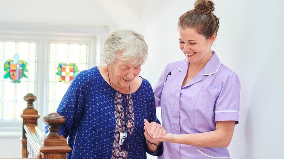 Nurse helping an older woman up the stairs