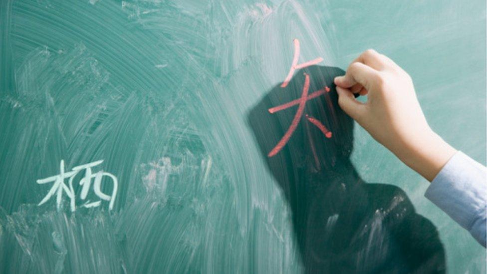 Someone writing Chinese on a blackboard