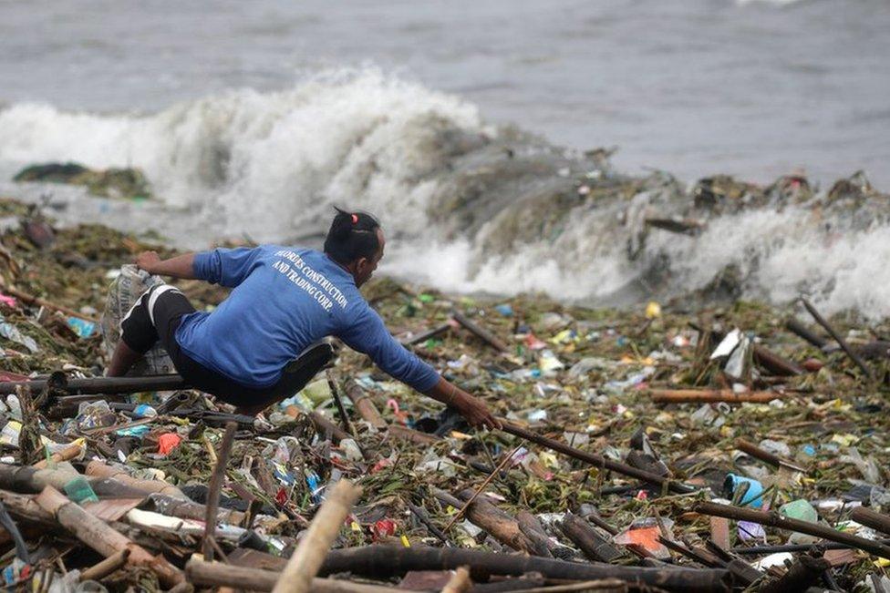 A man collects washed up rubbish along the shore of Manila Bay, Philippines, 26 July 2023 during typhoon Doksuri