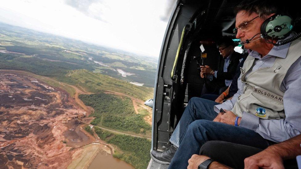 Brazilian President Jair Bolsonaro sits inside a helicopter flying over the area affected by the dam burst near Brumadinho