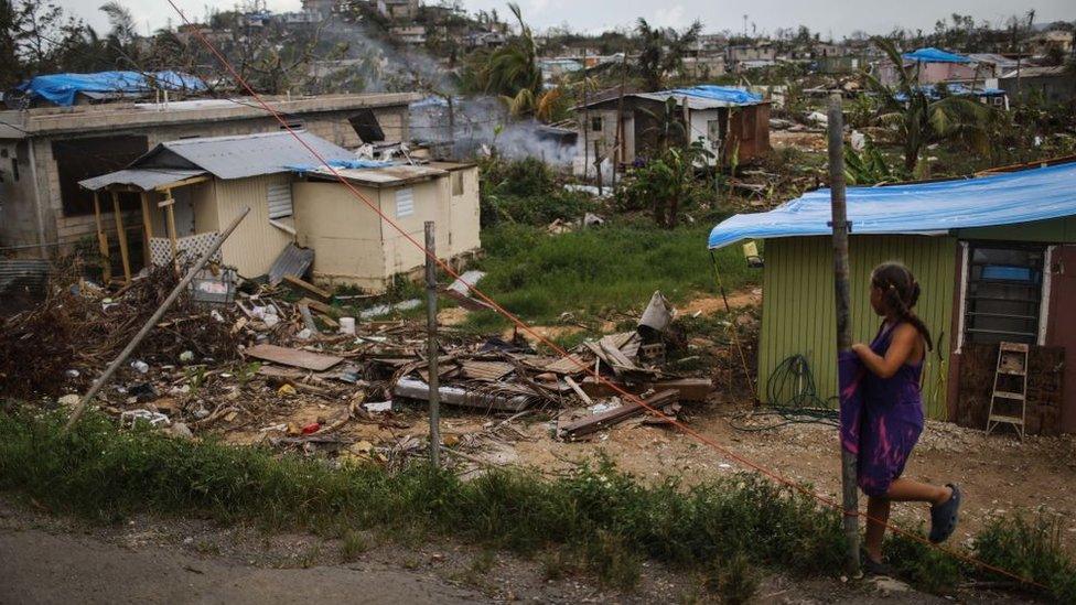 A girl stands near her house in an area without grid power or running water about two weeks after Hurricane Maria swept through the island on October 5, 2017 in San Isidro, Puerto Rico.