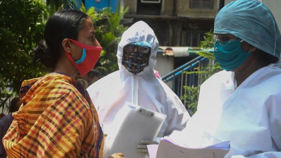 Municipal workers in hazmat suits talk to people waiting for a checkup at a municipal health camp during a government-imposed nationwide lockdown as a preventive measure against the COVID-19 coronavirus, in Kolkata on April 29, 2020.