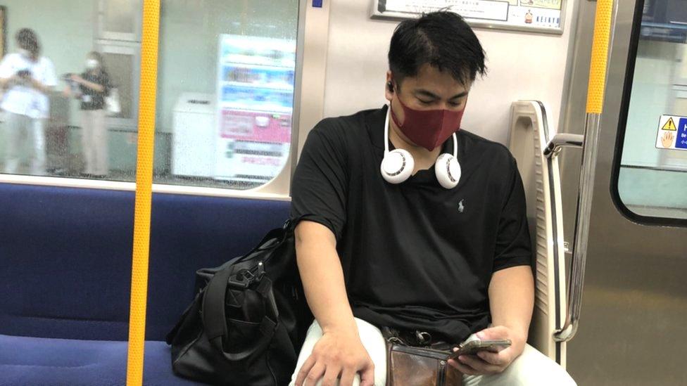 A neck fan being worn on the Tokyo Metro