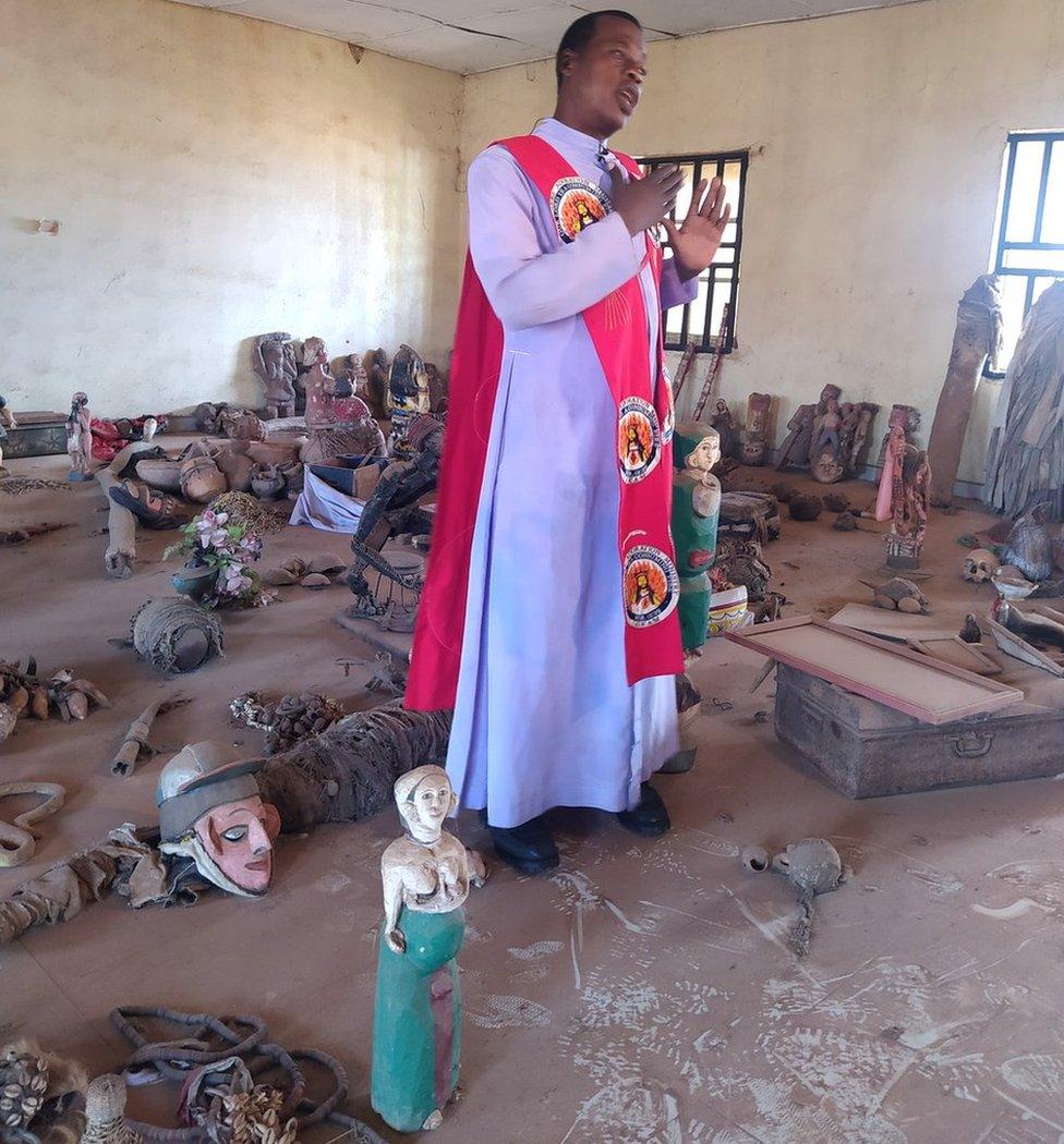 Pastor Obayi standing with artefacts littered on the floors