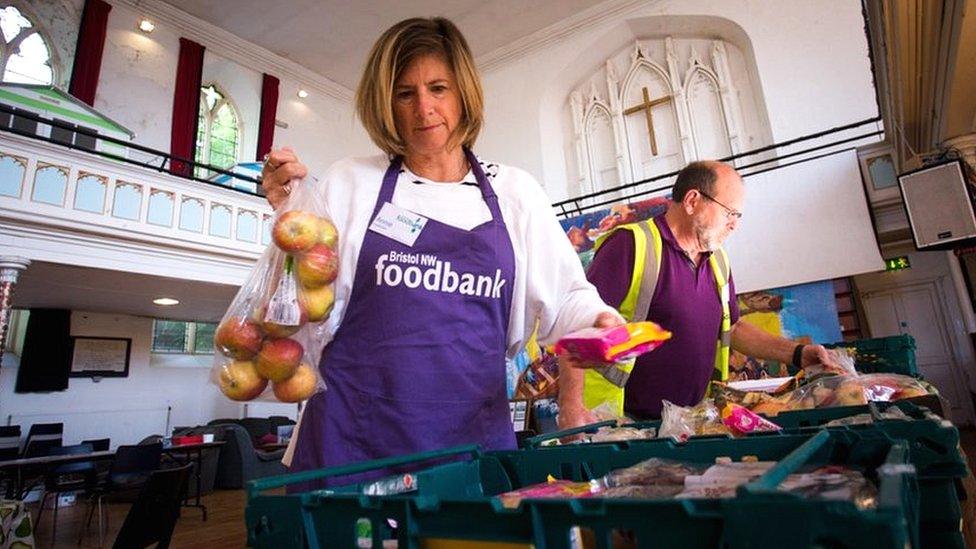 A woman wearing a purple apron working at a Foodbank