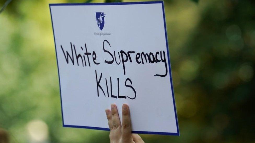 A woman holds a sign during a rally against guns and white supremacy in the wake of mass shootings in Dayton and El Paso