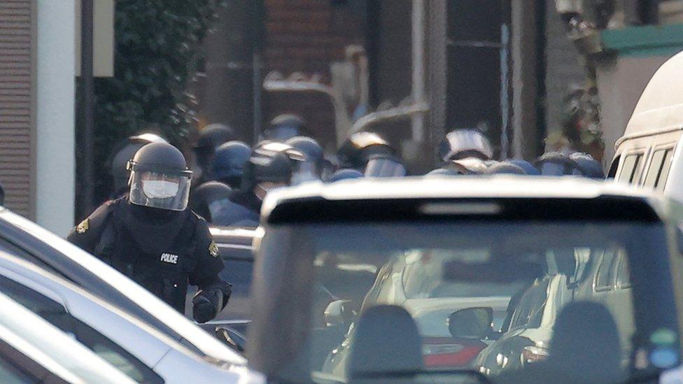 Police officers in riot protection rushed to cover the home during the hostage situation