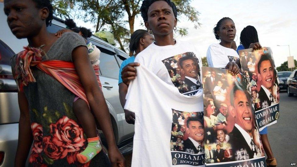 A woman walks past Kenyan hawker selling posters and T-shirts with the image of US President Barrack Obama