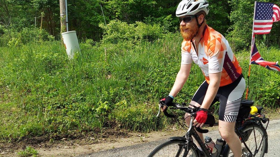 A man cycling along a road with plants in the background