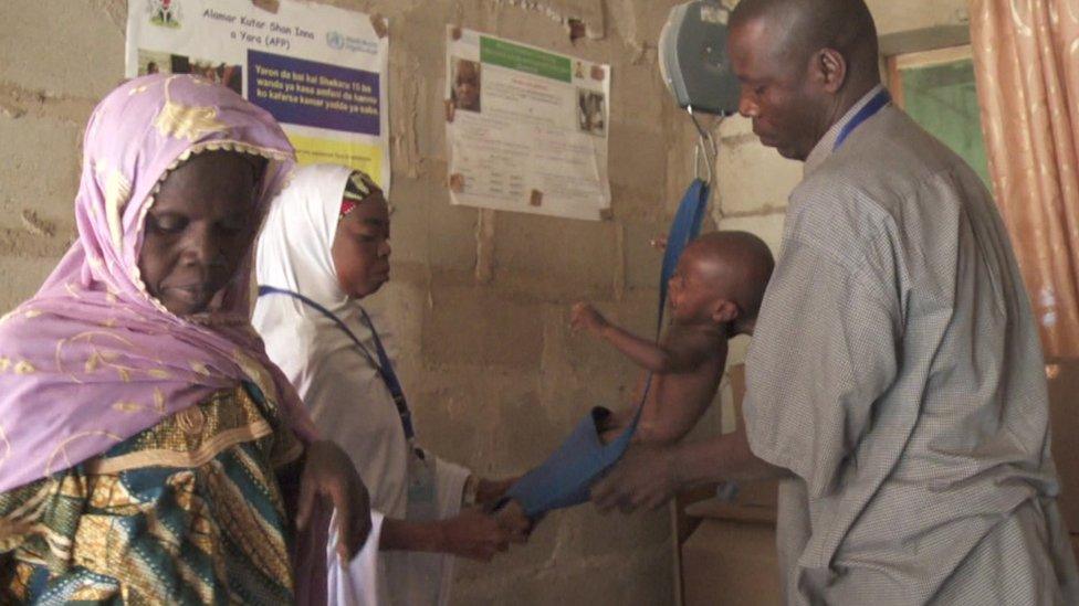 Health workers weigh a baby in Dalori camp in Nigeria