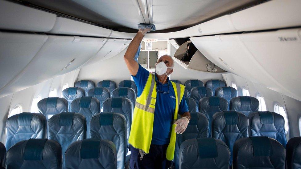 An airline worker wearing a face mask inspects a plane