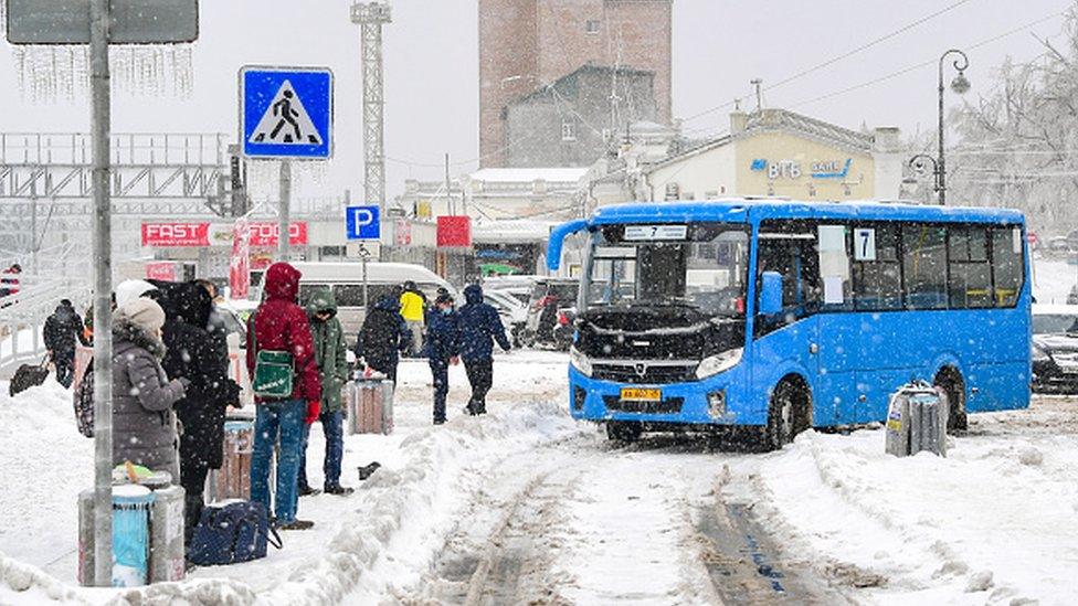 People wait at a bus stop during a snowstorm in Vladivostok